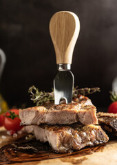 selective focus. deep-fried marbled pork steak in rustic style. on a wooden board, with coarse salt and spices. low key, close-up
