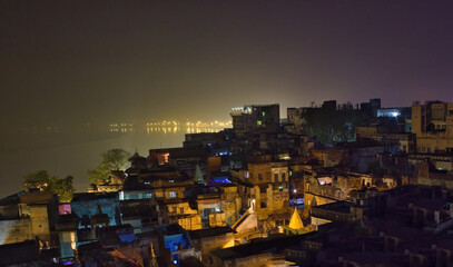 Fototapeta premium Historical indian city Varanasi, view over rooftop of the poor brick buildings, India. Banaras cityscape during night time