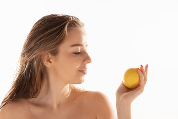 Obraz na płótnie Canvas Young beautiful girl posing with oranges isolated on white studio background. Concept of beauty, cosmetics, spa. Side view