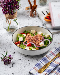 Bowl of fresh tuna salad with cheese on decorated background