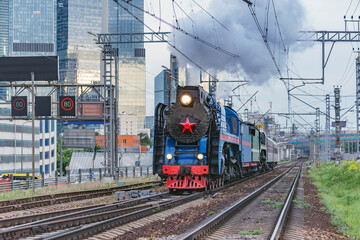 Retro steam train on Moscow city background.