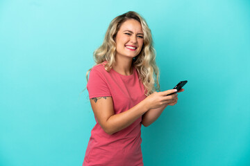 Fototapeta premium Young Brazilian woman isolated on blue background sending a message or email with the mobile