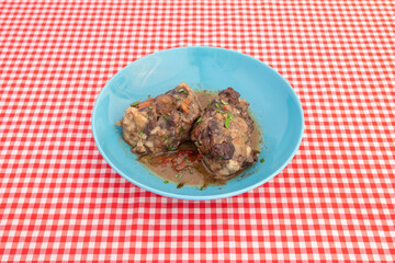 Pork cheek stewed with Pedro Ximenez wine on a blue deep plate