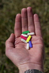 Own hand holding colorful pills at sunlight.