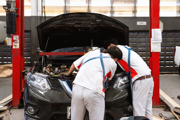 mechanic is checking the car in automobile repair service center with soft-focus and over light in the background