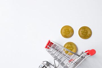 golden bitcoin in shopping cart on white table background. top view