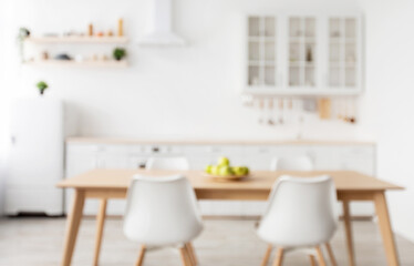 Blurred background of light kitchen interior in scandinavian style with wooden dining table, copy space