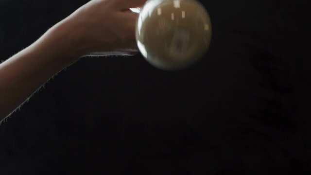 Vintage glass hourglass, inverted by a woman's hand on a black background