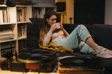 woman relaxing at home, listening records on gramophone