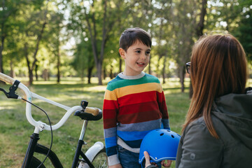 Obraz premium mother and her child in public park preparing to ride a bike