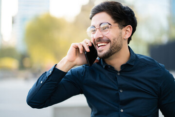 Young man talking on the phone outdoors.