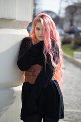 a girl with long pink hair stands up and looks into the lens, she is wearing a Basco belt