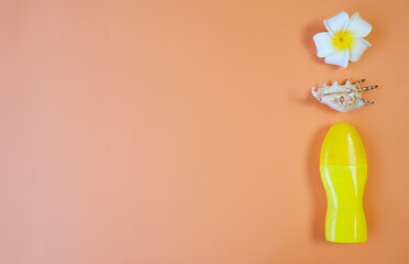 One yellow cosmetic bottle, tube, seashell and plumeria flower on orange background with space for text on the left. Natural sunscreens. cosmetic beauty concept. Mockup Top view.