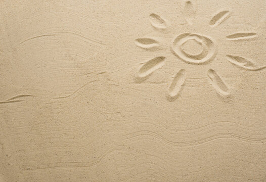 Sand texture with painted sun. Empty space for creative design or text. Relax on the sandy beach. Holidays and travel concept