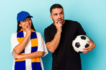 Young mixed race couple cleaning home isolated on blue background relaxed thinking about something looking at a copy space.