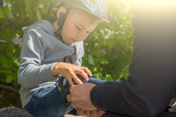 Father dad putting protection helmet for cycle on his son. Help and caring for children. City safety on scooter or bicycle