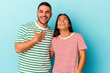 Naklejka premium Young mixed race couple isolated on blue background laughs out loudly keeping hand on chest.