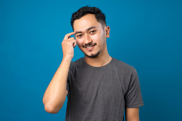 Young handsome man with beard wearing casual t-shirt over blue background Smiling pointing to head with one finger, great idea or thought, good memory