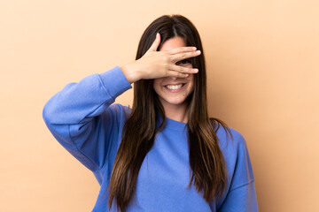 Teenager Brazilian girl over isolated background covering eyes by hands and smiling