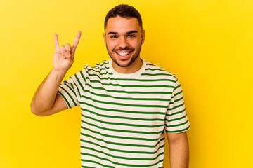 Fototapeta premium Young caucasian man isolated on yellow background showing a horns gesture as a revolution concept.