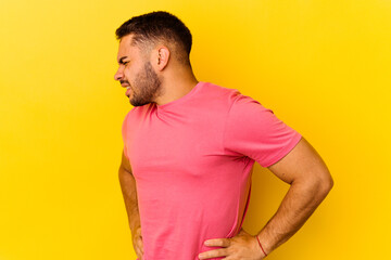 Obraz premium Young caucasian man isolated on yellow background suffering a back pain.