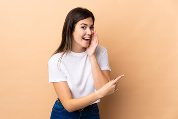 Fototapeta premium Teenager Brazilian girl over isolated background pointing to the side to present a product and whispering something