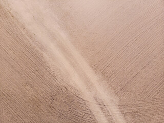 A plowed field with a path. Texture, background. Aerial photo