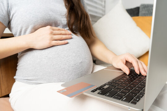 Online shopping on the Internet. Pregnant girl at the computer, pays for children's shopping with a card
