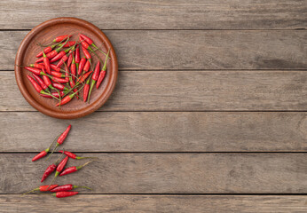 Red malagueta peppers on a plate over wooden table with copy space