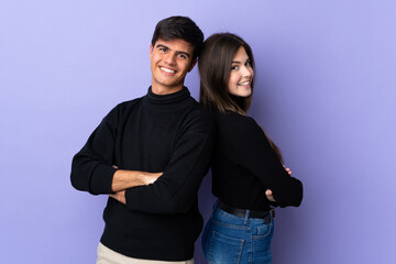Young couple over isolated purple background keeping arms crossed