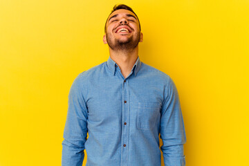 Young caucasian man isolated on yellow background laughs and closes eyes, feels relaxed and happy.