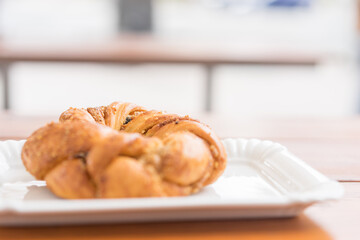 Freshly baked bagel on a white flat plate in a bakery on a table outdoors. Selective focus. Beautiful bokeh