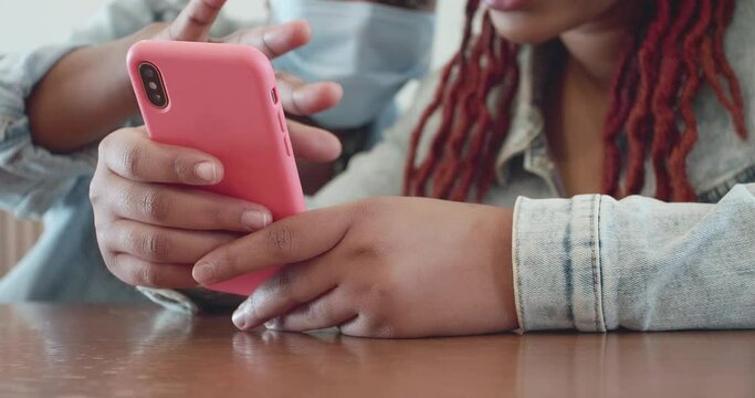 Two afro women use one smartphone in a pink case
