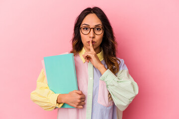 Young student mexican woman isolated on pink background keeping a secret or asking for silence.