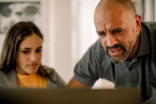 Father and daughter using laptop in kitchen