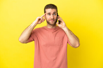 Fototapeta na wymiar Handsome blonde man using mobile phone over isolated background having doubts and thinking