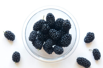  Mulberry fallen from a glass bowl on a white background