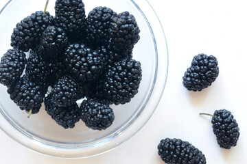  Mulberry fallen from a glass bowl on a white background