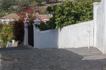 Stone walls enclosing cobbled alley descent In Tavira Portugal