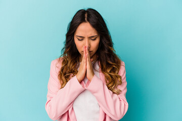 Young mexican woman isolated on blue background praying, showing devotion, religious person looking...