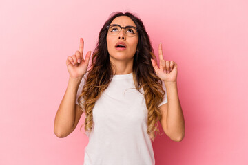 Young mexican woman isolated on pink background pointing upside with opened mouth.