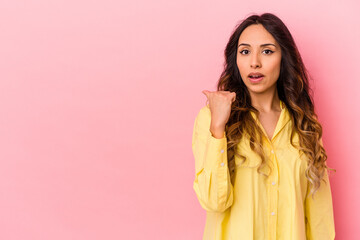 Young mexican woman isolated on pink background points with thumb finger away, laughing and carefree.