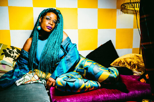 Portrait of confident woman with blue hair sitting on sofa in living room