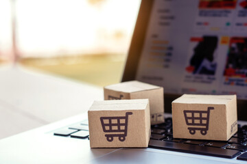 Shopping online. Cardboard box with a shopping cart logo on laptop keyboard. Shopping service on The online web. offers home delivery