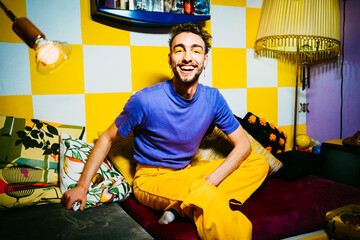 Portrait of cheerful young man sitting on sofa in living room