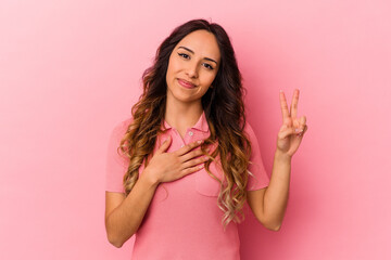 Young mexican woman isolated on pink background taking an oath, putting hand on chest.