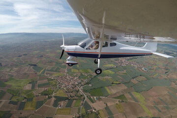 PILOT IN A SINGLE-ENGINE AIRPLANE WITH A HIGH WING FLYING OVER THE VILLAGES OF AZOFRA AND ALESANCO SURROUNDED BY CROP FIELDS IN THE PROVINCE OF LA RIOJA