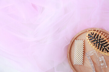 Comb with hair clip in wooden tray on pink background. top view, copy space.