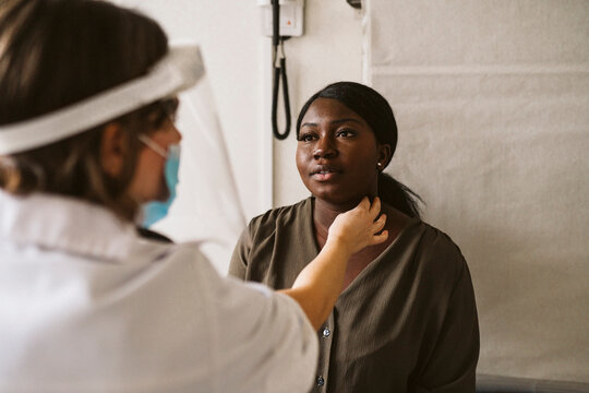 Female doctor checking pulse of young patient at medical clinic during COVID-19