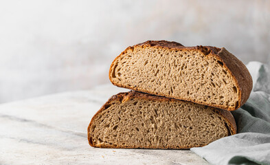 Freshly baked rye bread on a light concrete background, linen napkin. Place for your text. Freshly baked sourdough bread. Pastry items.